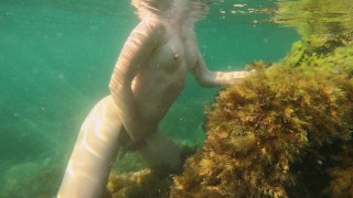 Szczupła dziewczyna pływa nago w morzu i masturbuje swoją cipkę